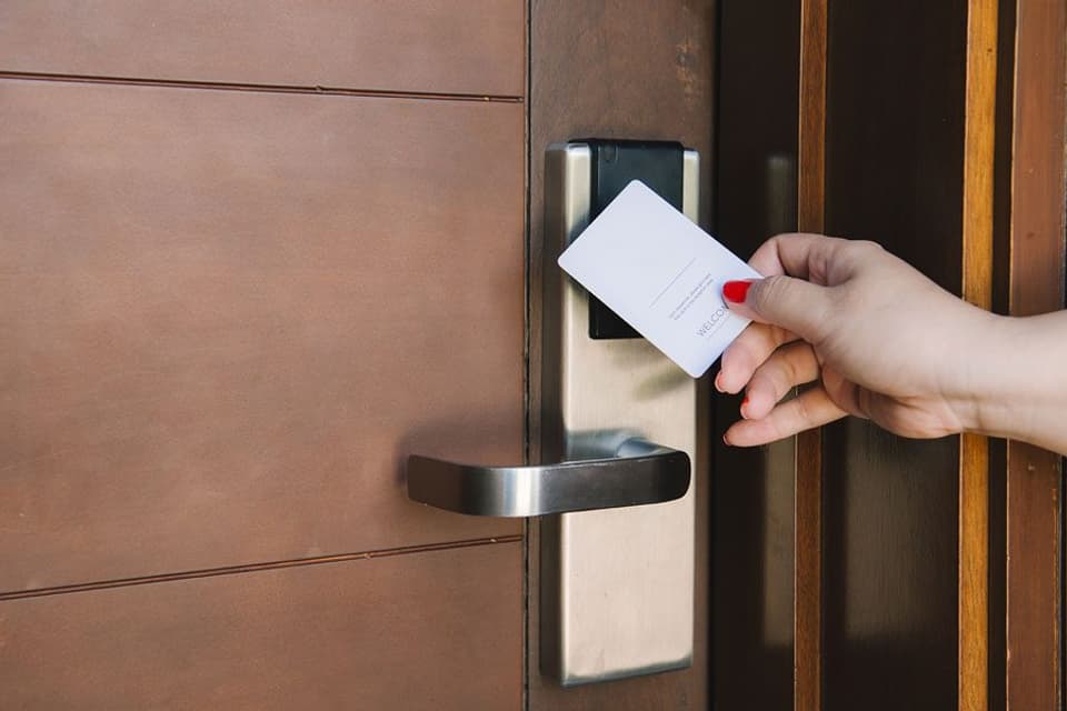 A hand holds a card up to the electronic lock on a hotel room door