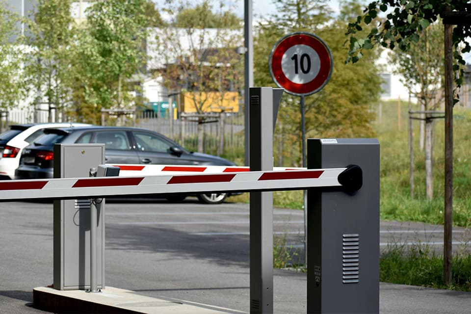 Lowered automatic barrier at a car park entrance with a car waiting